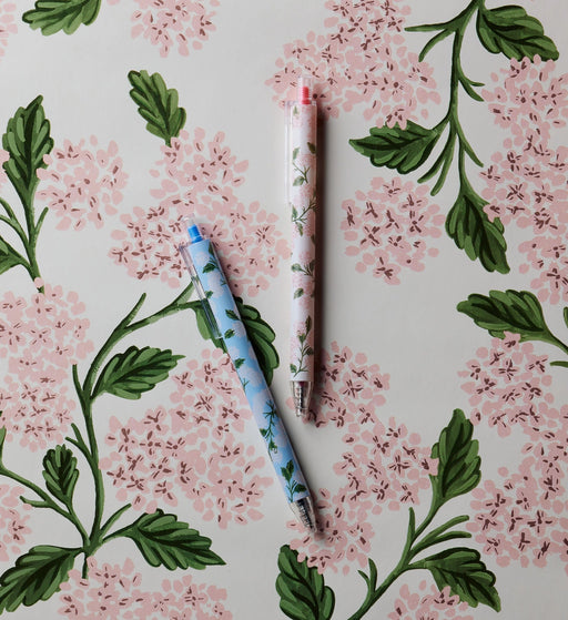Two pens on a floral-patterned surface