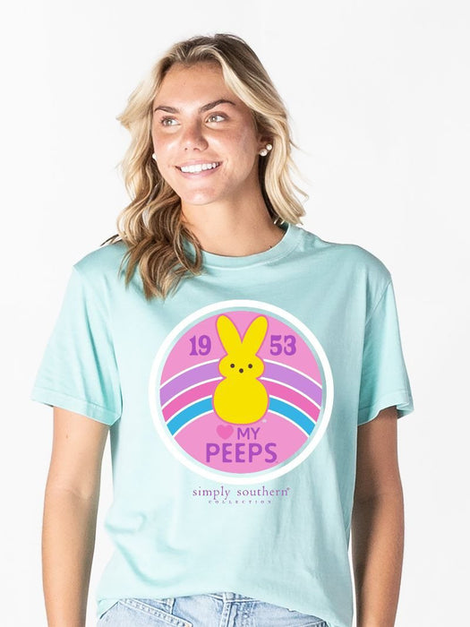 Woman wearing a light blue t-shirt with a colorful graphic design featuring a bunny and text.