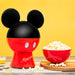 Red and black popcorn maker shaped like Mickey Mouse with a bowl of popcorn on a yellow background
