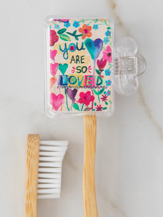 Bamboo toothbrush with a colorful case featuring floral designs and text on a light background.
