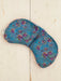 Blue floral-patterned eye pillow on a light wooden surface