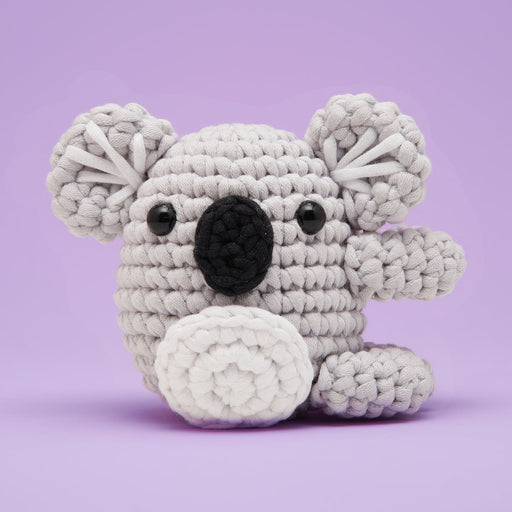Crocheted koala toy on a purple background