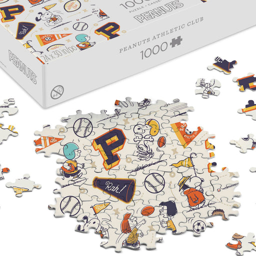 Peanuts-themed puzzle with pieces scattered on a white surface, box in the background