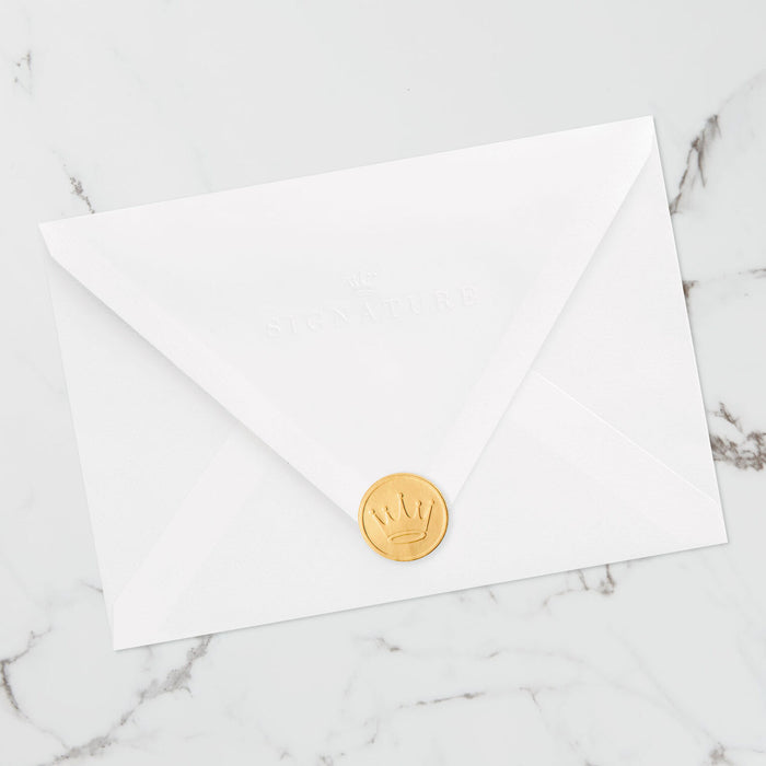 White envelope with a gold crown-shaped wax seal on a marble surface