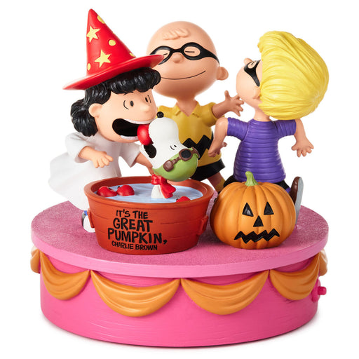 A Peanuts Halloween-themed collectible figurine set on a pink round base. The scene shows Charlie Brown in a wizard hat, Lucy in a purple dress, Snoopy, and a jack-o'-lantern pumpkin, with a red bucket labeled 'IT'S THE GREAT PUMPKIN, CHARLE BROWN' in the center.