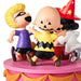 A collectible figurine set of three Peanuts characters dancing on a pink and orange tiered platform against a white background. The characters are dressed in Halloween costumes: a blonde figure in a purple shirt, a bald figure in a yellow and black zigzag shirt, and a figure in a red wizard hat and white robe.