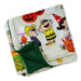 A folded fleece blanket featuring a colorful cartoon print from Peanuts with Halloween characters and pumpkins, showing a dark green sherpa backing.