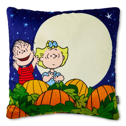 A square decorative pillow featuring a colorful Peanuts Halloween-themed illustration with Charlie Brown, Snoopy, pumpkins, and a full moon on a dark blue starry background.