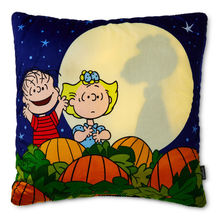 A square plush throw pillow featuring a Peanuts Halloween design with Charlie Brown and Snoopy in front of a large full moon and pumpkins, shown on a white background.