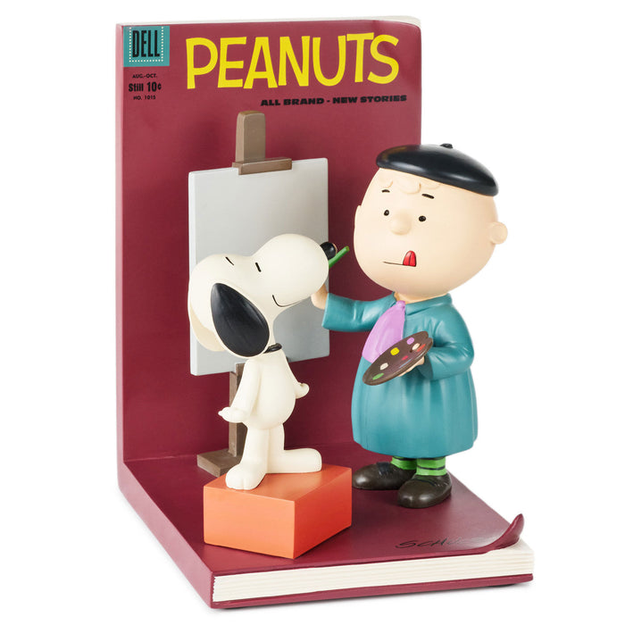 Figurine of a cartoon character painting a dog with a 'Peanuts' comic book in the background