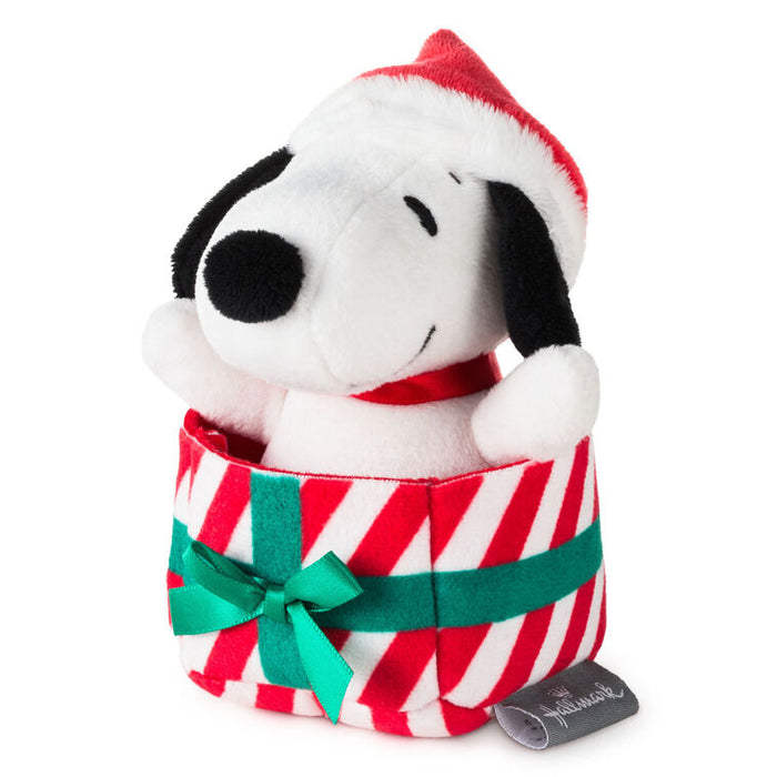 Plush toy resembling a dog in a Christmas-themed gift box with a red and white striped pattern and green ribbon.