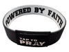 Black and white wristband with 'Powered by Faith' and 'Tap to Pray' text on a white background