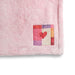 Pink textured blanket with a colorful patch featuring a red heart on a white background