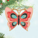 Butterfly-shaped ornament with pink, blue, and black design hanging on a tree.