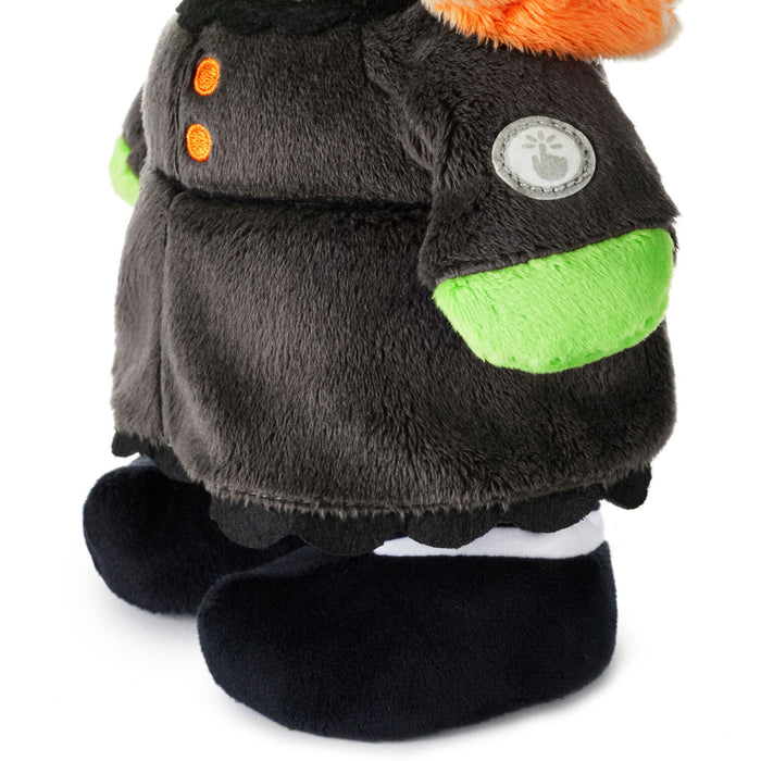 A close-up of a plush toy wearing a dark gray fuzzy jacket with bright green accents, orange buttons, and an orange fluffy trim, shown on a white background.