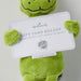 Green plush toy holding a Hallmark gift card holder with branding.