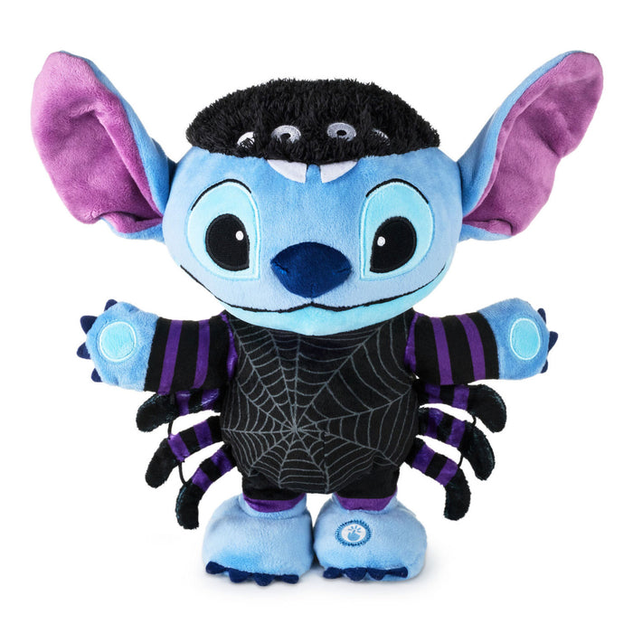 A Stitch plush toy styled as a spider, featuring a light blue body, purple inner ears, a black spiderweb-patterned chest, and purple and black striped arms and legs, set against a plain white background.