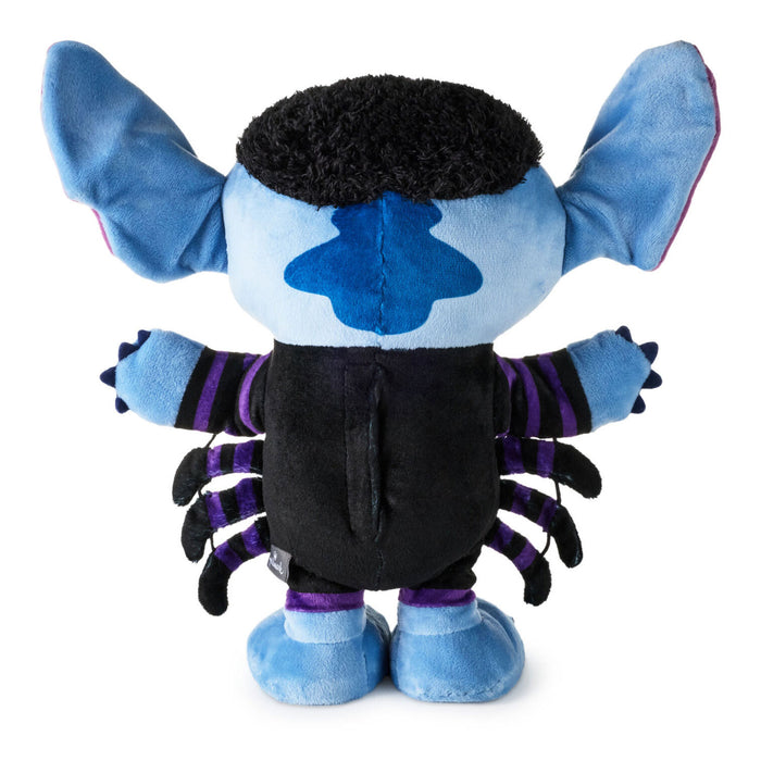 A plush toy character shown from the back, featuring light blue fabric, a black fuzzy head, a blue star-shaped patch on the back, a black body, and purple-striped arms and legs, photographed on a plain white background.