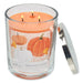 Three-wick candle in a glass jar with a pumpkin design on the label, on a white background.