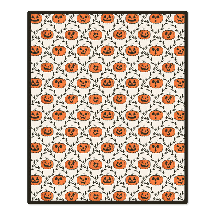 A rectangular area rug with a repeating Halloween pattern of orange jack-o'-lantern pumpkins and black vines on an off-white background, finished with a black border.