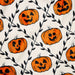 A close-up of a white fabric with an all-over Halloween pattern featuring orange jack-o'-lantern pumpkins and black vine branches.