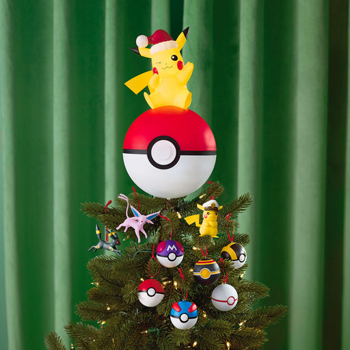 Christmas tree with Pikachu and Poké Ball decorations against a green curtain background