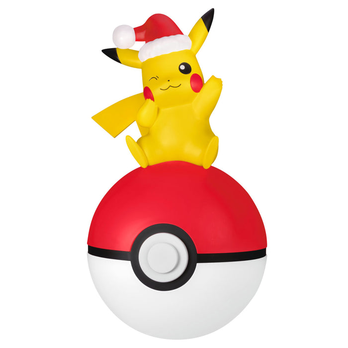 Pikachu figurine with a Santa hat on top of a Poké Ball against a white background