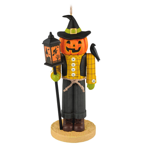 Halloween-themed ornament with a pumpkin face, lantern, and broom on a white background