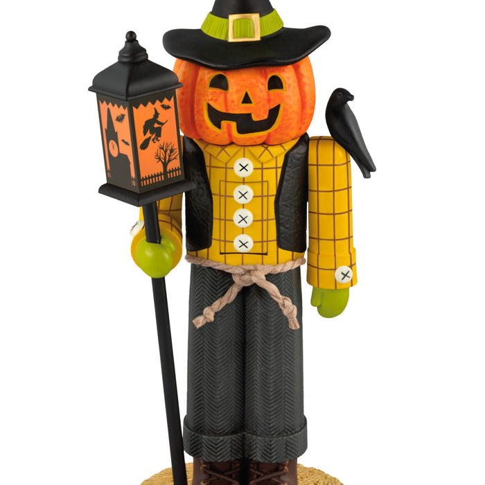 Halloween-themed nutcracker with pumpkin head, lantern, and broom on a white background