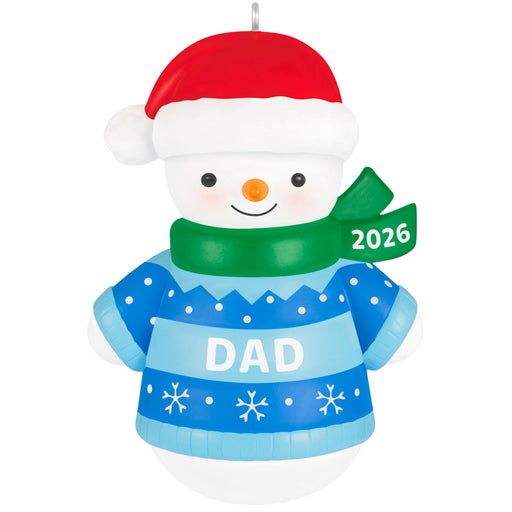 Snowman ornament with a blue sweater labeled 'DAD' and a red hat, wearing a green scarf with '2026' on a white background.