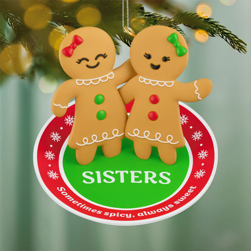 Gingerbread sister ornament with decorative text on a Christmas tree background