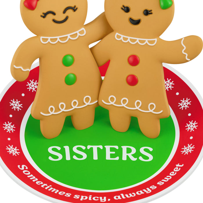 Two gingerbread cookies with the word 'SISTERS' on a decorative background