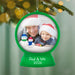 Personalized Christmas ornament with a photo of a man and a child wearing Santa hats, surrounded by snowmen, against a blurred Christmas tree background.