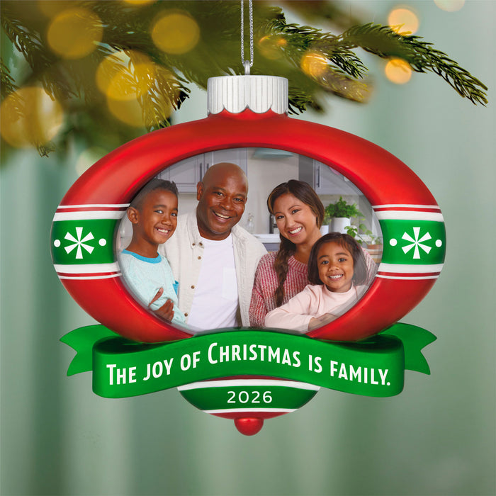 Decorative Christmas ornament with a family photo and 'The Joy of Christmas is Family' text, hanging on a tree.