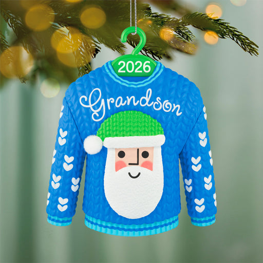 Blue sweater ornament with Santa face and 'Grandson' text, hanging on a Christmas tree.