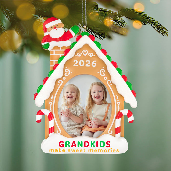 Christmas ornament shaped like a gingerbread house with Santa Claus, two children, and '2026' on a green background.