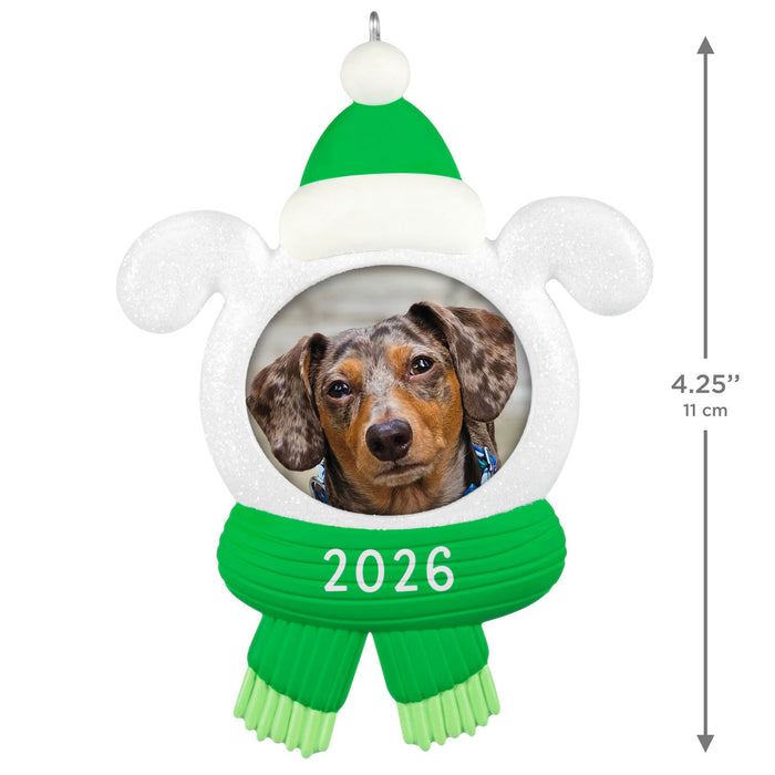 Decorative ornament with a dog photo, green hat, and scarf with '2026' on a white background.