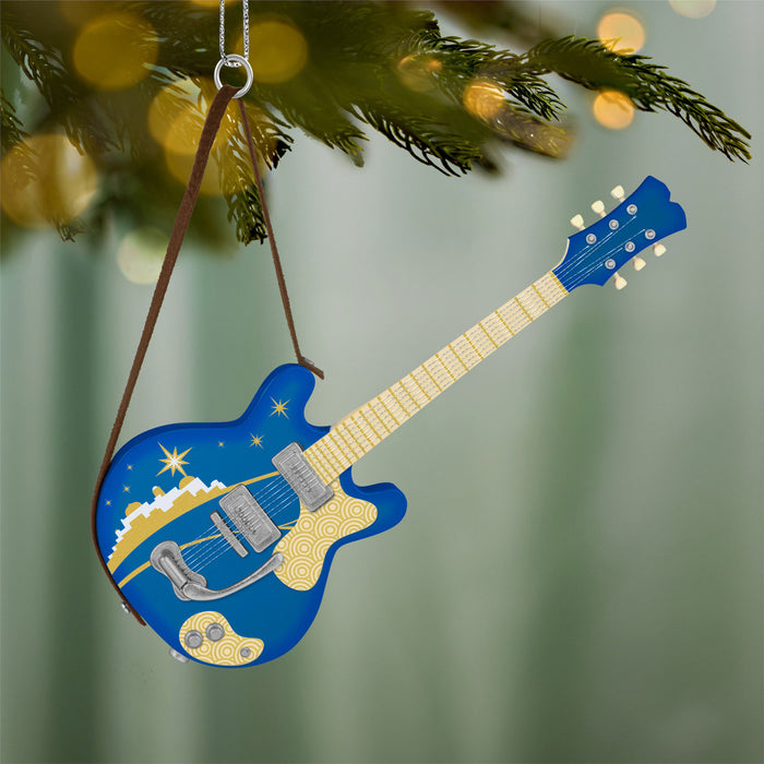 Blue electric guitar ornament hanging on a Christmas tree with blurred lights in the background.