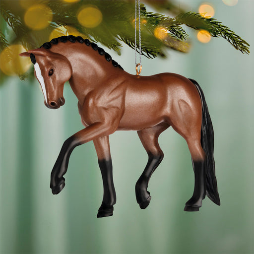 Brown horse ornament hanging on a Christmas tree with blurred lights in the background