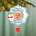 Christmas ornament with a baby's photo and snowman, labeled 'My Very First Christmas 2026', hanging on a tree.