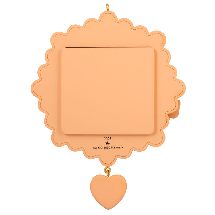 Peach-colored decorative item with scalloped edge and heart charm on a white background