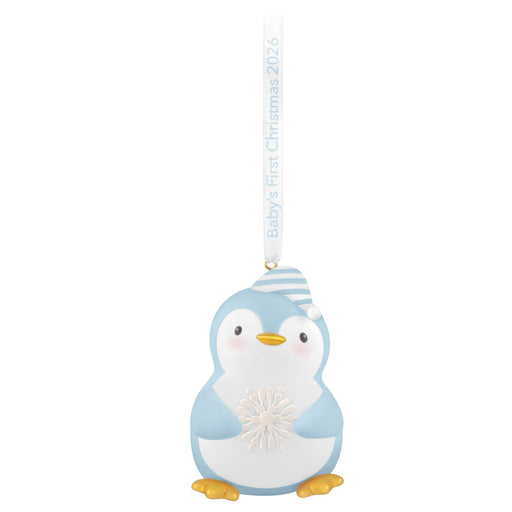 Decorative blue penguin ornament with a baby's first Christmas 2026 tag on a white background