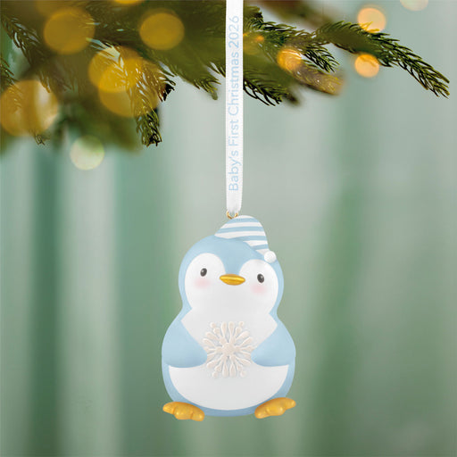 Penguin ornament hanging on a Christmas tree with a blurred green background