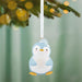 Penguin ornament hanging on a Christmas tree with a blurred green background
