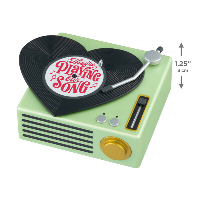 Miniature green record player with a vinyl record on a white background