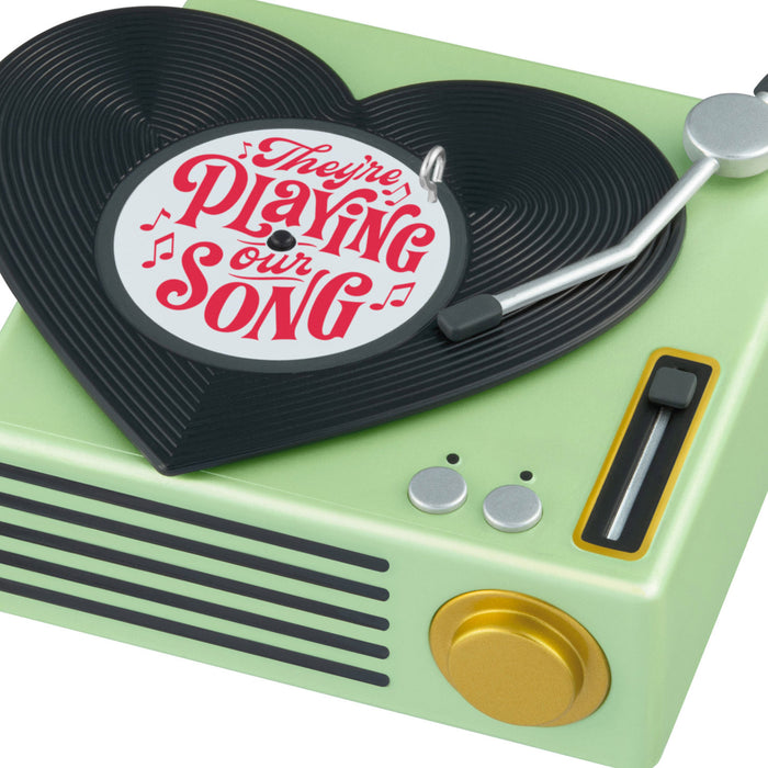 Vintage-style record player with a 'They're Playing Our Song' label on a white background