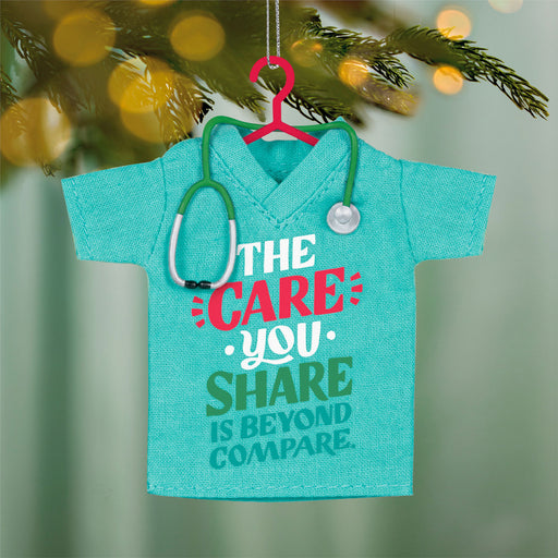 Decorative ornament shaped like a turquoise shirt with a stethoscope, featuring text on a blurred green background.