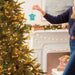 Person decorating a Christmas tree with a horse ornament in a festive living room.