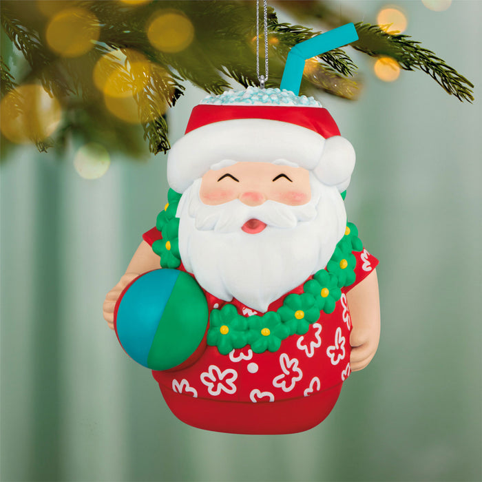 Santa Claus ornament in a beach-themed outfit with a ball, hanging on a Christmas tree.