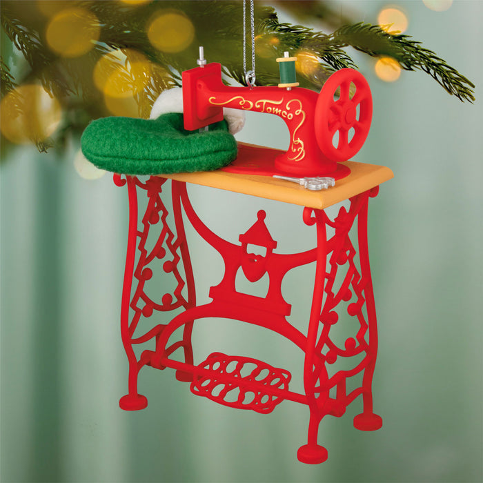 Red sewing machine ornament on a blurred Christmas tree background